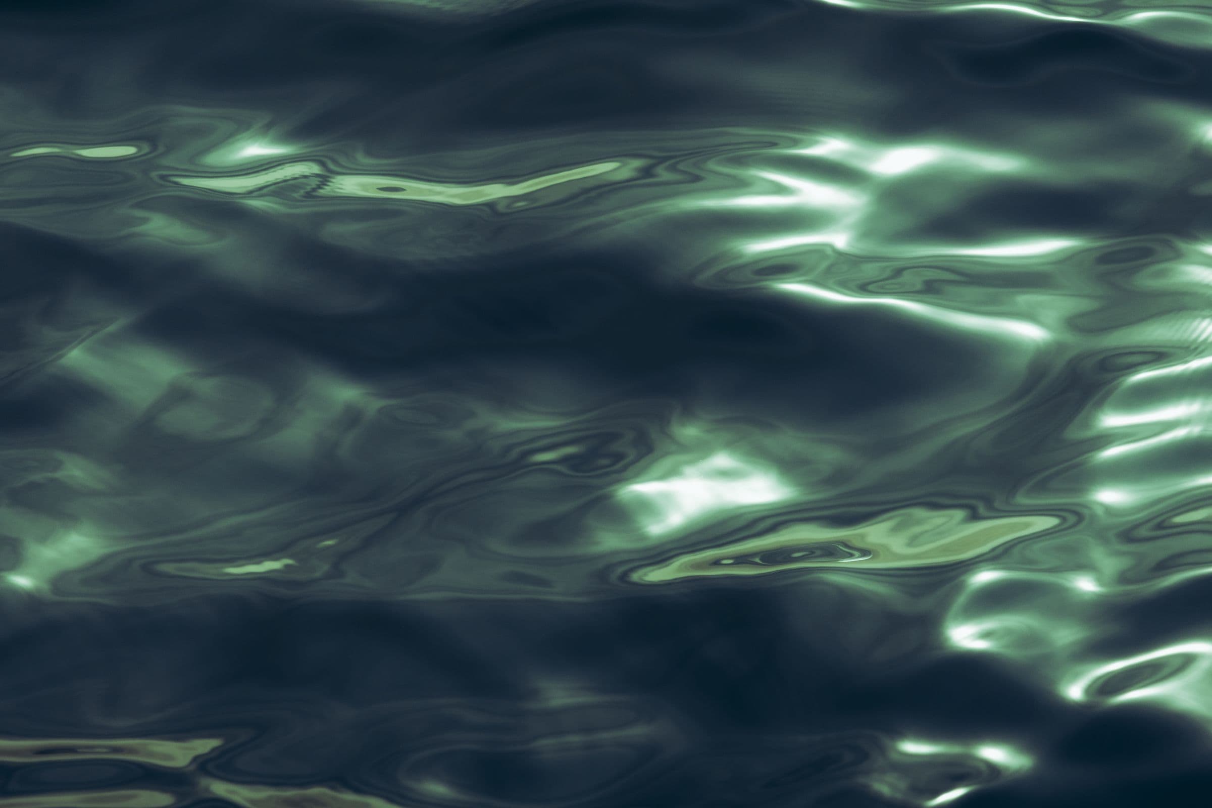 Abstract green ripples across a dark water surface